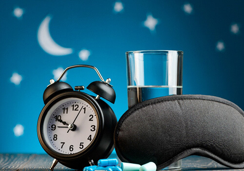 clock, pills, glass of water, and mask on nightstand