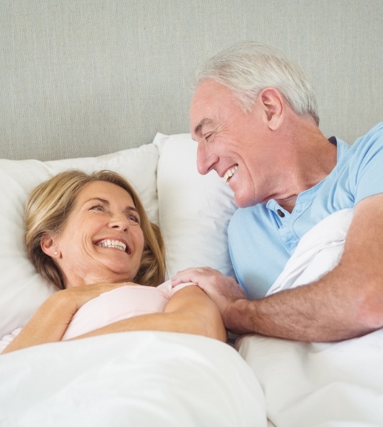 Man and woman waking up smiling after visiting Glendale sleep center