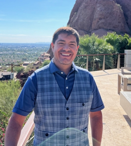 Glendale Arizona sleep apnea dentist Doctor Roger Roybal standing on balcony with trees and rock wall in background
