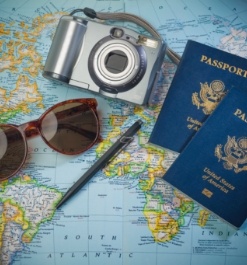 Two passports a pen a camera and sunglasses laying on world map