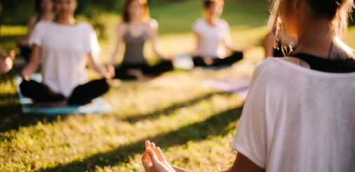 Meditation class taking place in grassy field