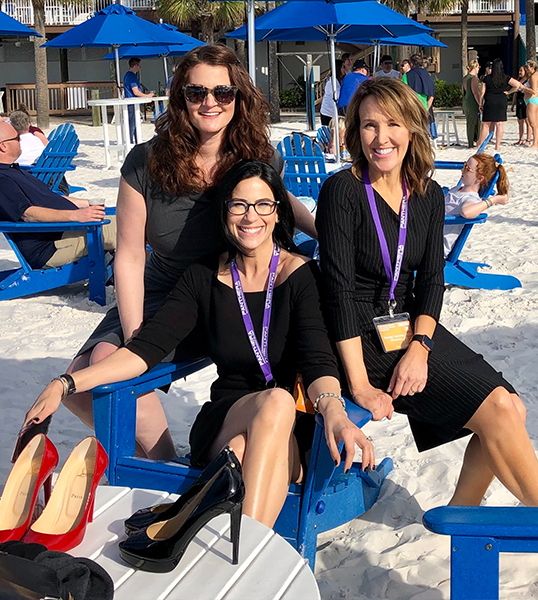 Three Glendale sleep apnea team members in black dresses sitting in wooden chairs on beach