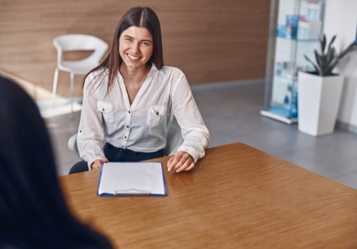 Young woman with clipboard sitting at desk