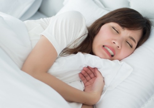 Woman wincing while laying in bed