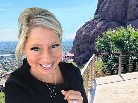 Angela with balcony green trees and rock face in background