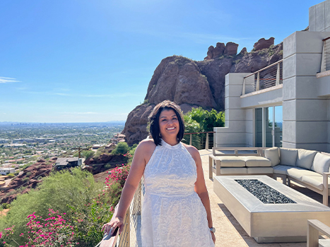 Claudia wearing white dress on balcony