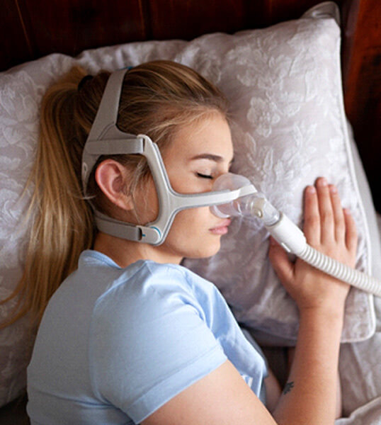 young woman sleeping and wearing a nasal CPAP mask