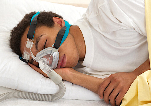young man sleeping and wearing a nasal CPAP