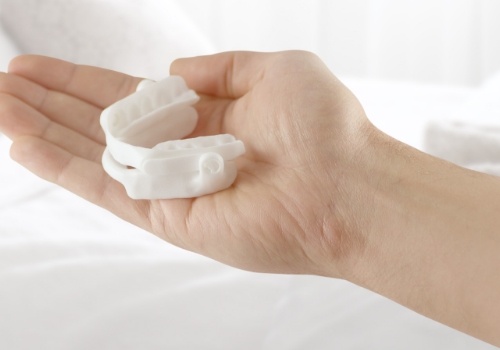Hand holding a white oral appliance