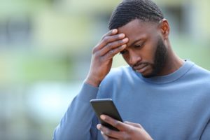 man looking at phone with concerned expression 