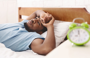 Man lying awake in bed looking concerned